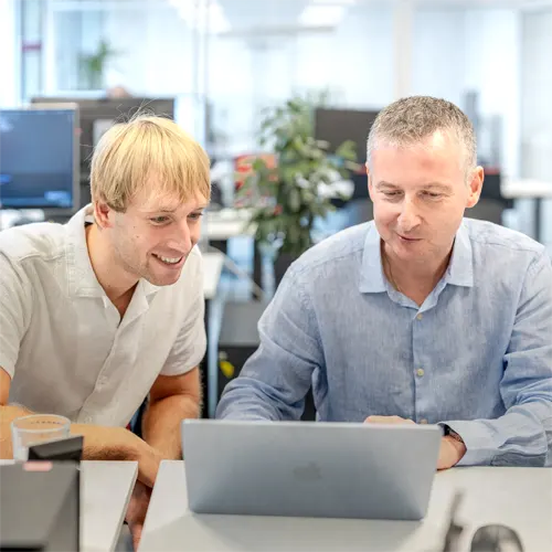 Zwei Mitarbeiter von Datalizard schauen auf einen Laptop.