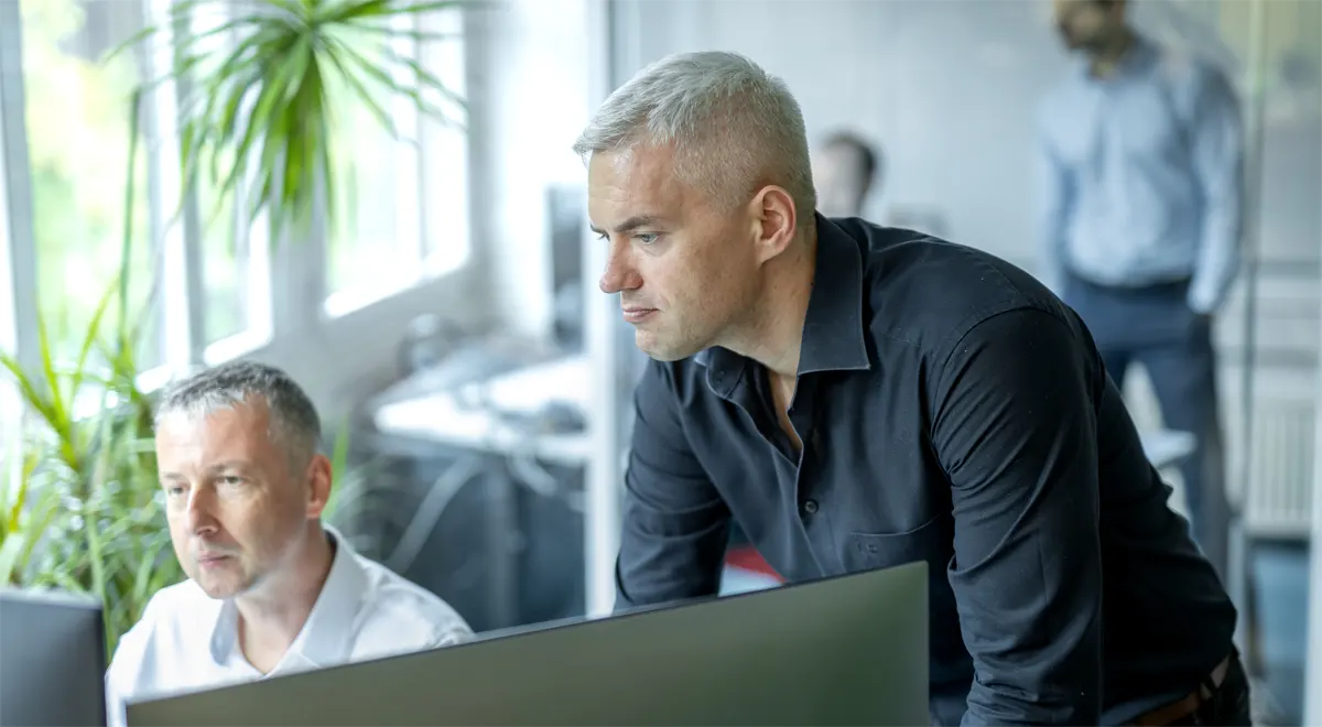 Zwei Datalizard-Mitarbeiter stehen konzentriert vor einem Computer.